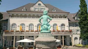 Das &ldquo;Gasthaus zur Margarethenh&ouml;he&rdquo; ist eins der ersten Geb&auml;ude der Siedlung, die zwischen 1909 und 1938 erbaut wurde. Heute beherbergt es ein Hotel und geh&ouml;rt zu den meistfotografierten Motiven des Stadtteils. Im Vordergrund der &bdquo;Schatzgr&auml;berbrunnen&ldquo;, ein Geschenk der Stadt Essen an die Stifterin Margarethe Krupp.