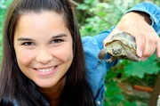 Die kleine Landschildkröte fühlt sich wohl in Annas Hand. Die kleine Landschildkröte fühlt sich wohl in Annas Hand.