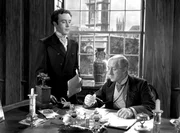 Louis Mazzini (Dennis Price, li.) arbeitet f&uuml;r den liebensw&uuml;rdigen Bankier (Alec Guiness), einer der wenigen aus der Familie, die eines nat&uuml;rlichen Todes sterben.