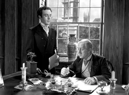 Louis Mazzini (Dennis Price, li.) arbeitet f&uuml;r den liebensw&uuml;rdigen Bankier (Alec Guiness), einer der wenigen aus der Familie, die eines nat&uuml;rlichen Todes sterben.