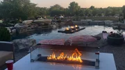 A tabletop, glass enclosed fire pit sits as a focal point within the patio furniture, tying the pool into the landscape by including fire in both. A tabletop, glass enclosed fire pit sits as a focal point within the patio furniture, tying the pool into the landscape by including fire in both.