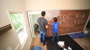 Ken Corsini (Left) and Anita Corsini white wash the brick wall to add character to their remodeled kitchen as seen on Flip or Flop Atlanta.