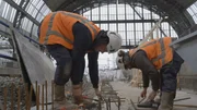 Jordy und Ivo arbeiten gemeinsam daran, Metallteile im Betonboden zu befestigen.