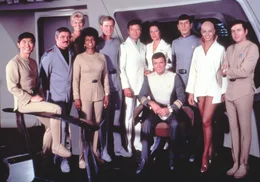 Die Besatzung der Enterprise von links: Lt. Commander Hikaru Sulu (George Takei), Lt. Commander Montgomery Scott (James Doohan), Janice Rand (Grace Lee Whitney), Lt. Commander Nyota Uhura (Nichelle Nichols), Commander Willard Decker (Stephen Collins), Dr. Leonard McCoy (DeForest Kelley), Dr. Chapel (Majel Barrett),  Admiral James T. Kirk (William Shatner), Commander Spock (Leonard Nimoy), Lieutenant Ilia (Persis Khambatta) und Lieutenant Pavel Chekov (Walter Koenig).