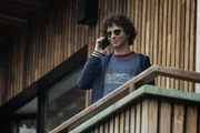 Ben (Shadi Eck) steht auf einem Balkon und telefoniert.