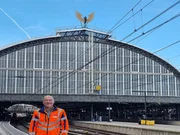 Bahnhofsvorsteher Ren&eacute; steht auf einem Bahnsteig, im Hintergrund ist der Bahnhof zu sehen.