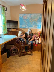Die B&auml;uerin zeigt den Enkelkindern das Spinnen am Handspinnger&auml;t.