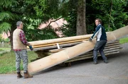 Sebastian (Dominik Stricker, re.) plagt sich allein mit schweren Bretterdielen f&uuml;r die Tenne ab, als v&ouml;llig unerwartet der seit 4 Wochen verschollene Manuel (Marco Canadea) angefahren kommt. Spontan packt er mit an.