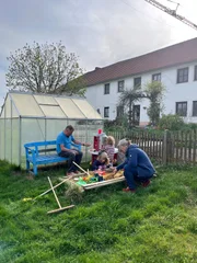 Die Altbauern spielen mit den Enkelkindern in der Sandkiste.