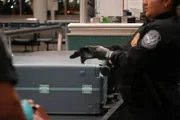 CBP-Beamter Lazo zieht Handschuhe an, um das Gep&auml;ck eines Verd&auml;chtigen am Newark Liberty International Airport zu kontrollieren. (National Geographic)