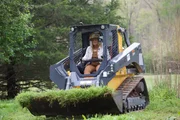 Misty Bilodeau digging up the ground with a small bulldozer to prepare for new garden beds. Misty Bilodeau digging up the ground with a small bulldozer to prepare for new garden beds.