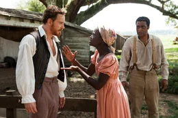 In die Sklaverei verkauft, f&auml;llt der einst freie Afroamerikaner Solomon (Chiwetel Ejiofor, r.) unter die Gewalt des brutalen Sklaventreibers Edwin Epps (Michael Fassbedner, l.), der seine Sklaven, wie die junge Patsey (Lupita Nyong'o, M.), auf sadistische Weise misshandelt ...