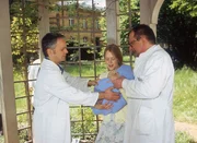 Das Kind, das Elsa Brandt (Anne Kanis) auf dem Arm trägt, hat offensichtlich Angst vor Dr. Friedrich (Rene Hofschneider, l.). (re. Komparse) Das Kind, das Elsa Brandt (Anne Kanis) auf dem Arm trägt, hat offensichtlich Angst vor Dr. Friedrich (Rene Hofschneider, l.). (re. Komparse)