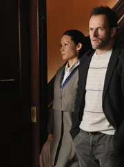 Anl&auml;sslich eines Abendessens lernt Holmes (Jonny Lee Miller, r.) die Familie von Watson (Lucy Liu, l.) kennen und kl&auml;rt sie &uuml;ber ihre Arbeit auf ...
