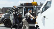 Das Verhalten eines Polizeiroboters beherrscht Chappie (Sharlto Copley, l.) als f&uuml;hlender Roboter nicht. Yankie (Jose Pablo Cantillo) setzt ihn der "echten Welt" aus, um ihn zum wahren K&auml;mpfer auszubilden.