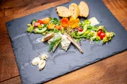 Es ist der Gruß aus der Küche zu sehen. Es gibt Räucherforellen-Filet auf Salat, dazu selbstgebackenes Treberbrot mit Forellenmuss. Es ist der Gruß aus der Küche zu sehen. Es gibt Räucherforellen-Filet auf Salat, dazu selbstgebackenes Treberbrot mit Forellenmuss.