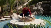 Wide Shot of Brian standing on fireplace table inside of pool installing net to fire pit, as seen on Pool kings. Wide Shot of Brian standing on fireplace table inside of pool installing net to fire pit, as seen on Pool kings.