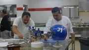 Danny cuts white fondant strips, Buddy cuts blue fondant strips.