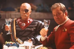 Der festliche Schein tr&uuml;gt: Captain James T. Kirk (William Shatner, re.) ist es gar nicht recht, mit Kanzler Gorkon (David Warner, li.) an einem Tisch sitzen zu m&uuml;ssen.