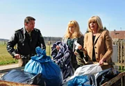 Auf der Suche nach Julius altem Morgenmantel, durchsuchen Charlotte (Mona Seefried, r.) und Rosalie (Natalie Alison, M.) die S&auml;cke einer Altkleidersammelstelle und werden promt von der Polizei (Komparse, l.) beim "Klauen" erwischt.