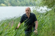 Dr. Henning Strahl (Christoph Tomanek) schleicht vorsichtig durch hohes Schilfgras.
