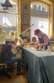 SWR HANDWERKSKUNST, "Wie man einen coolen M&auml;nnerhut macht". Modistin Elke Tombers schneidet das Futter f&uuml;r den handgefertigten Fedora-Hut zu. Im Bild: 1.v.l Bettina Lichtenauer Kamera, 2.v.l. Elke Tombers