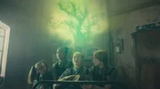 Felicitas (Dagny Rollins, 2.v.r.) ist eine "Gr&uuml;ne Hexe" - sie steht der Natur sehr nahe und kann sich mit ihr verbinden. Maude (Megan Hughes, l.), Edith (Tamara Smart 2.v.l.) und Mildred (Lydia Page, r.) beobachten, wie sie aus dem St&uuml;ck Holz, das von dem Baum stammt, den Esther zerst&ouml;rt hat, lesen kann: Ein m&auml;chtiger alter Zauber hat den Baum gesch&uuml;tzt und Esther muss sich aus tiefer &Uuml;berzeugung bei ihm entschuldigen, damit sie nicht selbst f&uuml;r immer ein Baum wird.