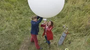 Fritz Fuchs (Guido Hammesfahr, l.) und die Forscherin Frau Mackelbatz (Adriana Altaras, r.) schicken einen Wetterballon los, um die herannahende Hagelfront zu erkunden.