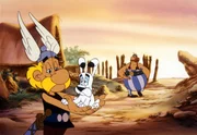Asterix (li.) und Idefix (Mi.) sind geschafft. Sie glauben, dass Obelix (re.) einen schlimmen Schaden verursachte indem er Miraculix mit einem riesigen Hinkelstein am Kopf getroffen hat.