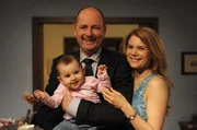Die junge Familie macht sich zum morgendlichen Aufbruch fertig. Von links: Franzi, Hubert Kirchleitner (Bernhard Ulrich) und Uschi Guggenmoser (Silke Popp).