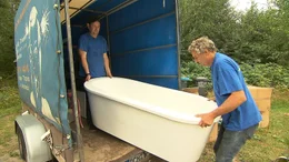 Frank B&ouml;hm und Kollege tragen Badewanne aus Transporter