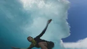 Justine Dupont blickt nach oben, w&auml;hrend sie auf einer Welle surft, die sich &uuml;ber ihr kr&auml;uselt.