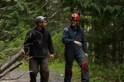 (L to R) Jason Storie and Andrew Munoz walking in the woods with caving gear on.
