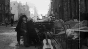 Eine alte Frau und Kind mit Habseligkeiten auf der Stra&szlig;e, 1943.