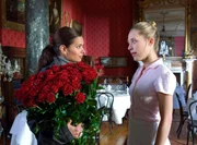 Lea (Sandra Speichert, li.) hat von ihrem Verflossenen einen Strau&szlig; Rosen geschickt bekommen und bittet Zimmerm&auml;dchen Lucy (Marisa Leonie Bach), sie als Tischdekoration zu verwenden.