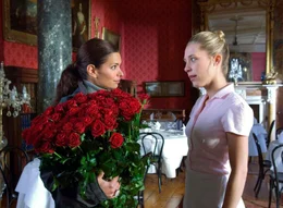 Lea (Sandra Speichert, li.) hat von ihrem Verflossenen einen Strau&szlig; Rosen geschickt bekommen und bittet Zimmerm&auml;dchen Lucy (Marisa Leonie Bach), sie als Tischdekoration zu verwenden.