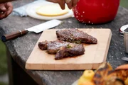Das mit Koriander-Pesto gefüllte Bison Rib-Eye-Steak wird mit Salz gewürzt. Das mit Koriander-Pesto gefüllte Bison Rib-Eye-Steak wird mit Salz gewürzt.
