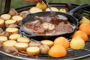 Bisonschulter in Biersoße mit geschmortem ganzen Knoblauch auf dem Grill, umzingelt von Kartoffeln und Zitrusfrüchten. Bisonschulter in Biersoße mit geschmortem ganzen Knoblauch auf dem Grill, umzingelt von Kartoffeln und Zitrusfrüchten.