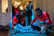 Haase (Fabian Harloff, l.) und sein Kollege k&uuml;mmern sich um die bewusstlose Bianca (Sinja Dieks, liegend), die w&auml;hrend dem Chaos auf einer Party offensichtlich die Treppe heruntergefallen ist.