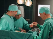 Als Dr. Roland Heilmann (Thomas R&uuml;hmann, rechts) und Dr. Philipp Brentano (Thomas Koch, links) das erste k&uuml;nstliche Knochenimplantat bei einer Probandin einsetzen, kommt sogar Prof. Simoni (Dieter Bellmann) wissbegierig in den OP.