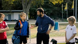 Trainer Rainer (Mohamed Achour) stellt Ben (Yoran Leicher) der Mannschaft des SC D&uuml;ren vor.