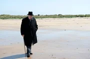 Winston Churchill (Brian Cox) denkt bei einem Spaziergang am Strand nach.