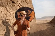 Die &Auml;gyptologin Colleen Darnell h&auml;lt einen Sonnenschirm in der Hand, w&auml;hrend sie vor der Grabst&auml;tte von Khasekhemwy steht. (Windfall Films/Alex Tough)