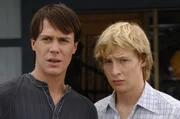 Lewis (Angus McLaren, re.) und Zane (Burgess Abernethy, li.) beobachten voller Entsetzen, wie Cleo, Emma und Rikki den unsympathischen Nate anhimmeln. Eine geheimnisvolle Tinktur macht ihn unwiderstehlich f&uuml;r die Meerjungfrauen.