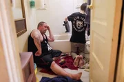 Mikal sp&uuml;lt das Geschirr in der Hotelbadewanne, w&auml;hrend sein Vater Jason ihm Gesellschaft leistet.
