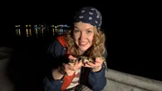 Nina hält ein junges Spitzkrokodil in der Hand, das gleich von einer Krokodilforscherin untersucht wird. Nina hält ein junges Spitzkrokodil in der Hand, das gleich von einer Krokodilforscherin untersucht wird.