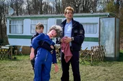 Jenny (Eva Bühnen, l.), die eine Übungspuppe fürs Schießtraining hält und Heino (Sebastian Schwarz, r.) schauen Marie hinterher, während sie ins Dorf fährt. Jenny (Eva Bühnen, l.), die eine Übungspuppe fürs Schießtraining hält und Heino (Sebastian Schwarz, r.) schauen Marie hinterher, während sie ins Dorf fährt.