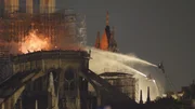 Wasserstrahlen versuchen verzweifelt, die Flammen zu l&ouml;schen, die Notre Dame verschlingen