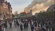 Zuschauer beobachten, wie am 15. April 2019 Flammen und Rauch vom Dach der Kathedrale Notre-Dame in Paris aufsteigen.