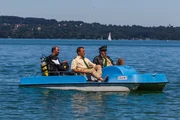 Hubert (Christian Tramitz, m.) und Staller (Helmfried von L&uuml;ttichau, r.) sitzen in einem Tretboot und fahren auf den See hinaus. Yazid (Hannes Ringlstetter, l.) sitzt hinter ihnen in Tauchermontur. Er soll f&uuml;r Hubert und Staller testen, ob man mit einem Schlittschuh unter Wasser an einer Boje h&auml;ngen bleiben kann.